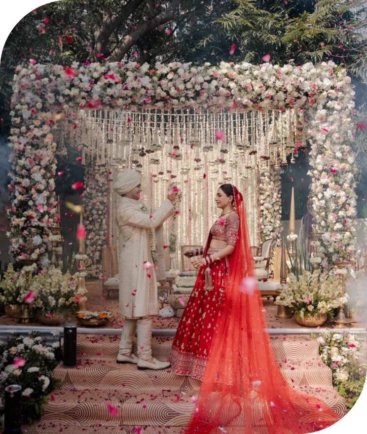 A couple exchanging garlands beneath a floral mandap